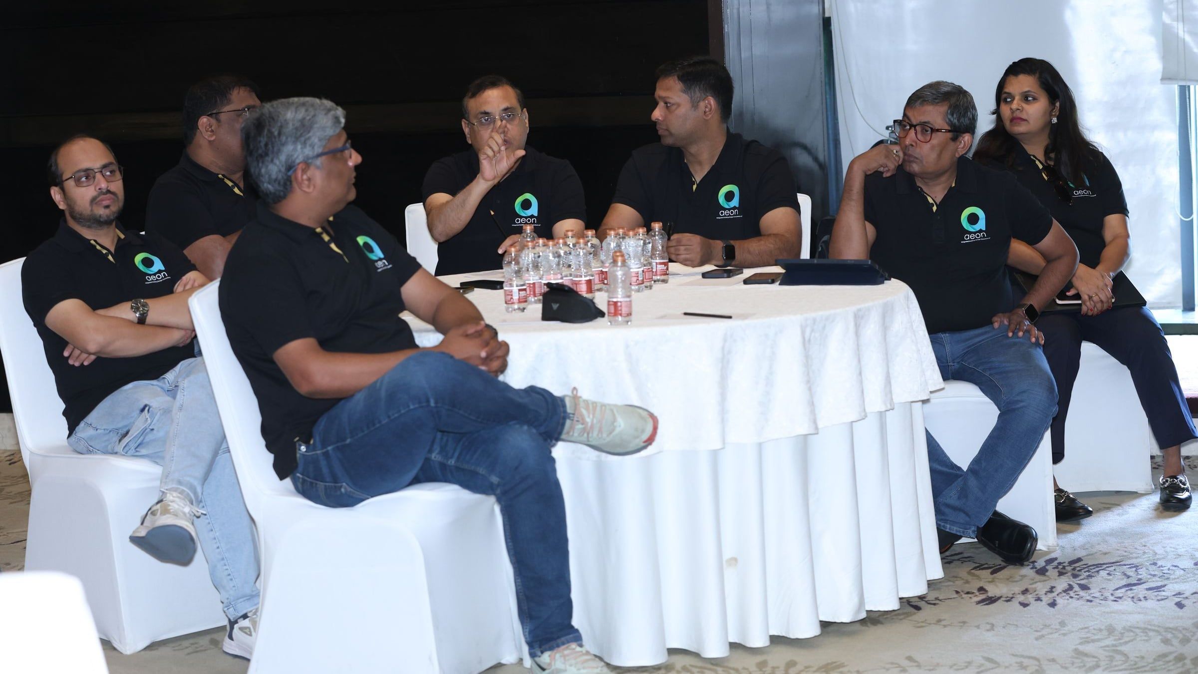 AEON's team in AEON shirts in discussion around a table at the leadership offsite